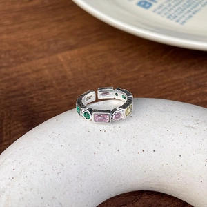Detailed macro view of silver open ring featuring colorful inlaid rectangle and round gems