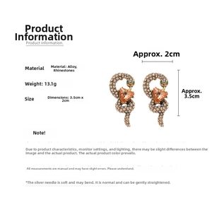 Detailed view of snake earrings featuring orange heart gems and sparkling rhinestones