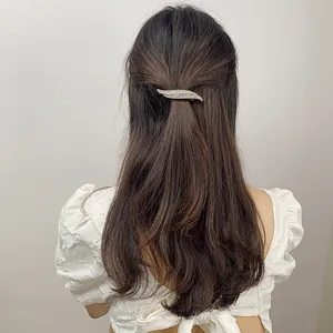 Detail of silver rhinestone feather hair clip worn on a half-up hairstyle for women