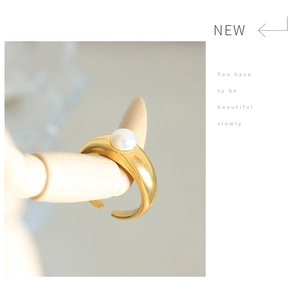 Close-up of a gold streamlined ring with a white freshwater pearl on a wooden hand model