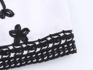 Close-up detail of ethnic style top featuring black floral embroidery and crochet lace trim