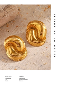 Detail of 18K gold plated spiral earrings with artistic texture on a stone background