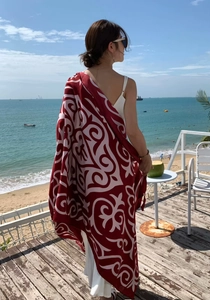 Back view of red polyester shawl with ethnic prints on a sunny seaside terrace