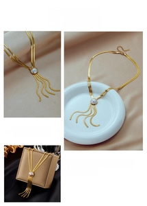 Dettaglio di una collana dorata a strati con cerchio in madreperla e nappe lisce