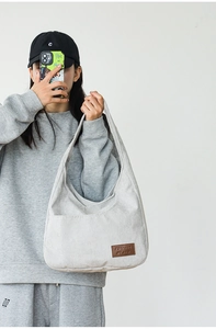 Close-up of light gray corduroy tote bag with embossed leather label on model