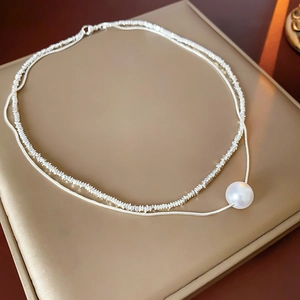 Détail du collier argenté à double épaisseur avec chaîne serpent et perle blanche ronde