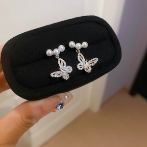 Detail of silver butterfly earring with three pearls and rhinestones on black velvet box