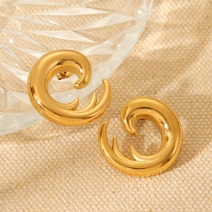 Macro shot of gold spiral wavy hoop earrings with a polished mirror finish on woven fabric
