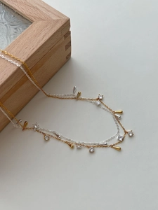 Dettaglio di collane in argento e oro con pietre di zircone e ciondoli a goccia