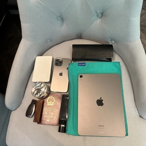 Portable nylon insert organizer bag with iPad, phone, and travel essentials on blue chair