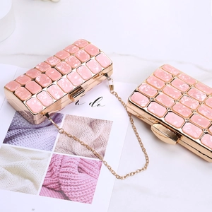 Detailed view of pink marble-pattern acrylic evening clutches with elegant gold chain strap