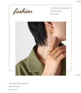 Close-up of gold padlock earrings with purple stones and textured rings on a model