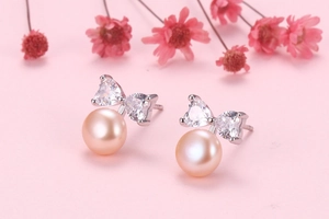 Macro shot of silver bow heart earrings with champagne pearls and white zircons