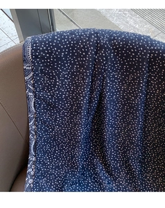 Detail of navy cotton linen scarf with white polka dots and floral border on fabric