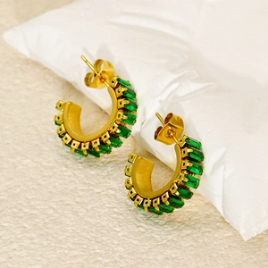 Macro detail of gold C-shape hoop earrings with emerald green square-cut zircon stones