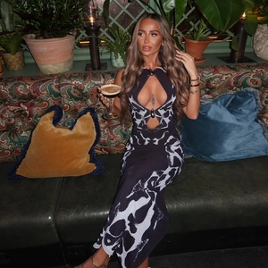Chic sleeveless leopard print maxi dress with halter neck and waist cutout on a green sofa