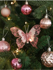 Détail de papillon rose pailleté avec ailes en maille sur un sapin de Noël festif