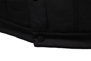 Dettaglio dell'orlo di una giacca in twill nero con bottone a scatto opaco e cuciture