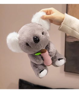 Close-up of plush koala toy with soft grey fur and leaf detail held by hands
