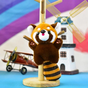 Vue détaillée d'un mignon porte-clés en peluche panda roux sur un support en bois