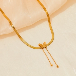 Gros plan d'un collier papillon doré à double couche avec pendentif givré et pompon