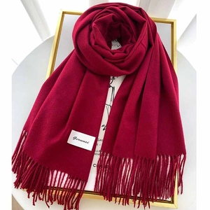 Close-up of a premium deep red solid cashmere scarf with elegant tassel fringe detail
