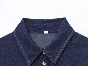 Detail of dark blue denim shirt collar with contrast stitching and metal buttons