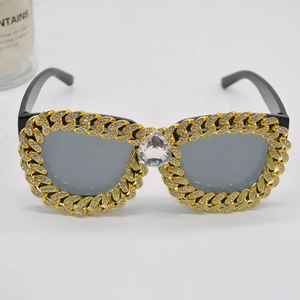 Detail of gold Cuban chain sunglasses with sparkling rhinestones and heart-shaped crystal