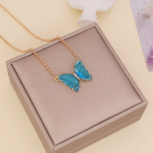 Golden chain necklace featuring a blue crystal butterfly pendant on a beige gift box
