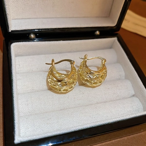 Detailed view of vintage hollow metal basket earrings in a premium black jewelry box