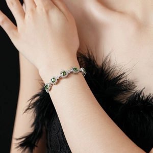 Détail d'un bracelet en argent avec pierres carrées vertes et diamants étincelants au poignet