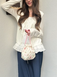 Detailed close-up showing a quilted floral drawstring storage bag being held by a model