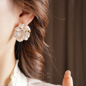 Gros plan sur la boucle d'oreille fleurie vintage avec pétales en nacre et cristal