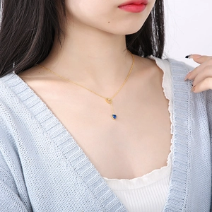 Close-up of heart-shaped blue sapphire pendant on gold chain worn by a model