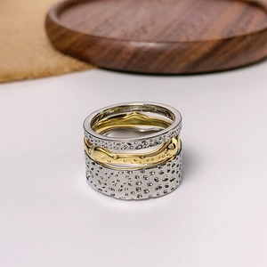 Detailed view of three stacked rings featuring silver hammered texture and gold wave band
