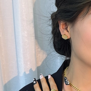 Élégantes boucles d'oreilles ovales dorées avec pierre vert pâle sur un mannequin