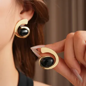 Boucles d'oreilles vintage dorées torsadées avec pierre ovale noire portées sur modèle