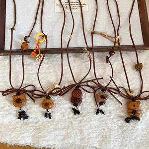Detail of five handmade wooden bear and star pendants on brown leather cords