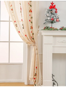 Close-up of cream lace curtain with Christmas bell embroidery and festive foliage detail