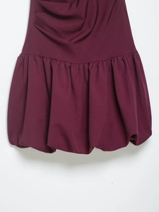 Vue détaillée d'une robe bordeaux avec ourlet ballon élégant et textures plissées fines