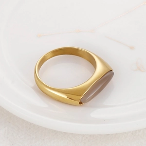 Detail of gold fishnet ring with gray oval gemstone on white ceramic constellation plate