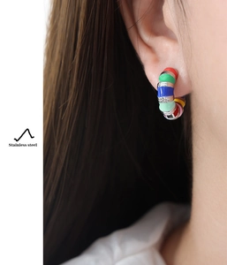 Macro shot of colorful enamel stainless steel hoop earrings on model's ear