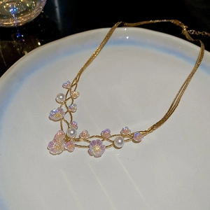 Detail of gold flower necklace with white pearls and iridescent petals on ceramic