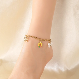 Détail d'une chevillère dorée avec pendentifs papillon, tournesol et nœud sur soie