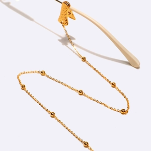 Detail of gold metal eyewear chain featuring hammered letter A charm and bead accents