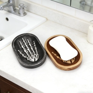 Detailed view of skull hand soap dishes in silver and bronze colors on a bathroom vanity