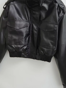 Close-up of black faux leather biker jacket featuring large pockets and rib-knit hem