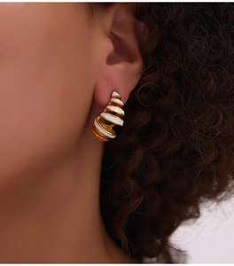 Macro side view of a minimalist spiral water drop earring with gold and white enamel coating
