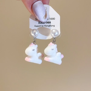 Detail of unicorn drop earrings with white flocking texture and delicate pearl studs