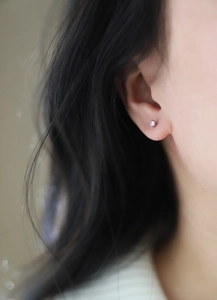 Close-up of pink round-cut birthstone stud earrings in silver titanium on ear